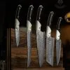 Custom handmade Damascus steel chef knife set with hammered blades and a premium leather roll bag.